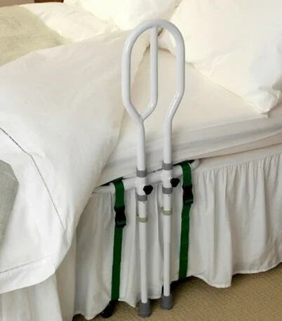 White bed assist rail with green straps attached to a bed with white bedding and bed skirt