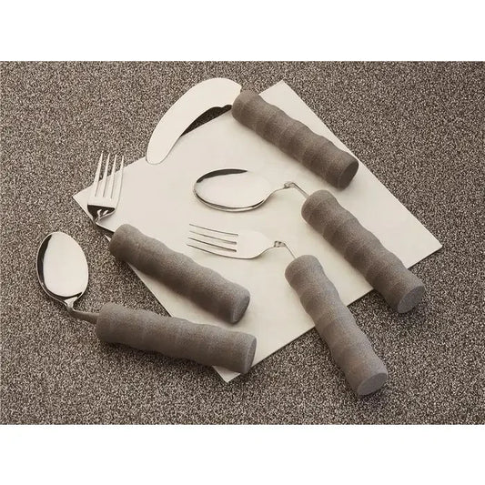 Adaptive utensils with gray padded ergonomic foam grips on forks and spoons on textured surface