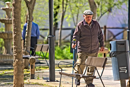a man walking down a sidewalk next to a park bench