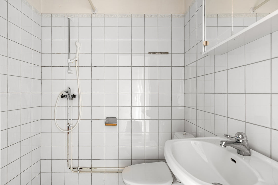 A white tiled bathroom with two sinks and a shower