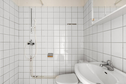 A white tiled bathroom with two sinks and a shower