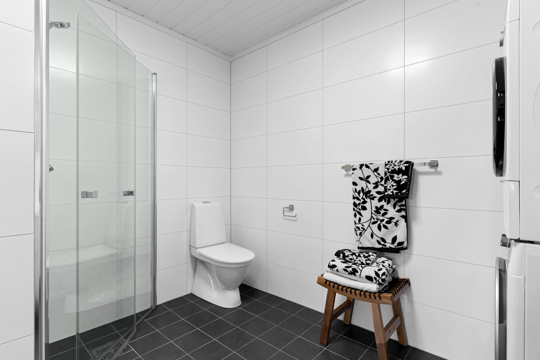 A bathroom with a toilet, shower, and a stool