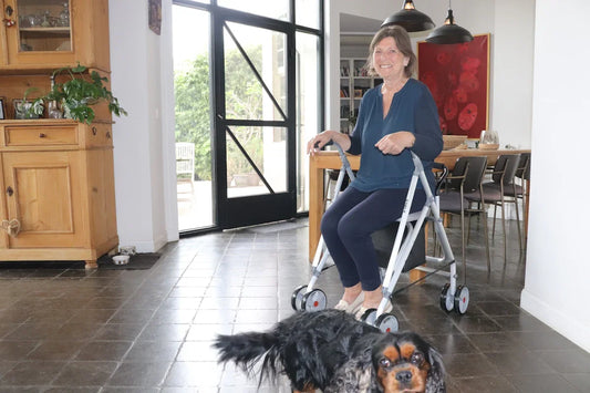 Woman uses a walker while a dog looks on.