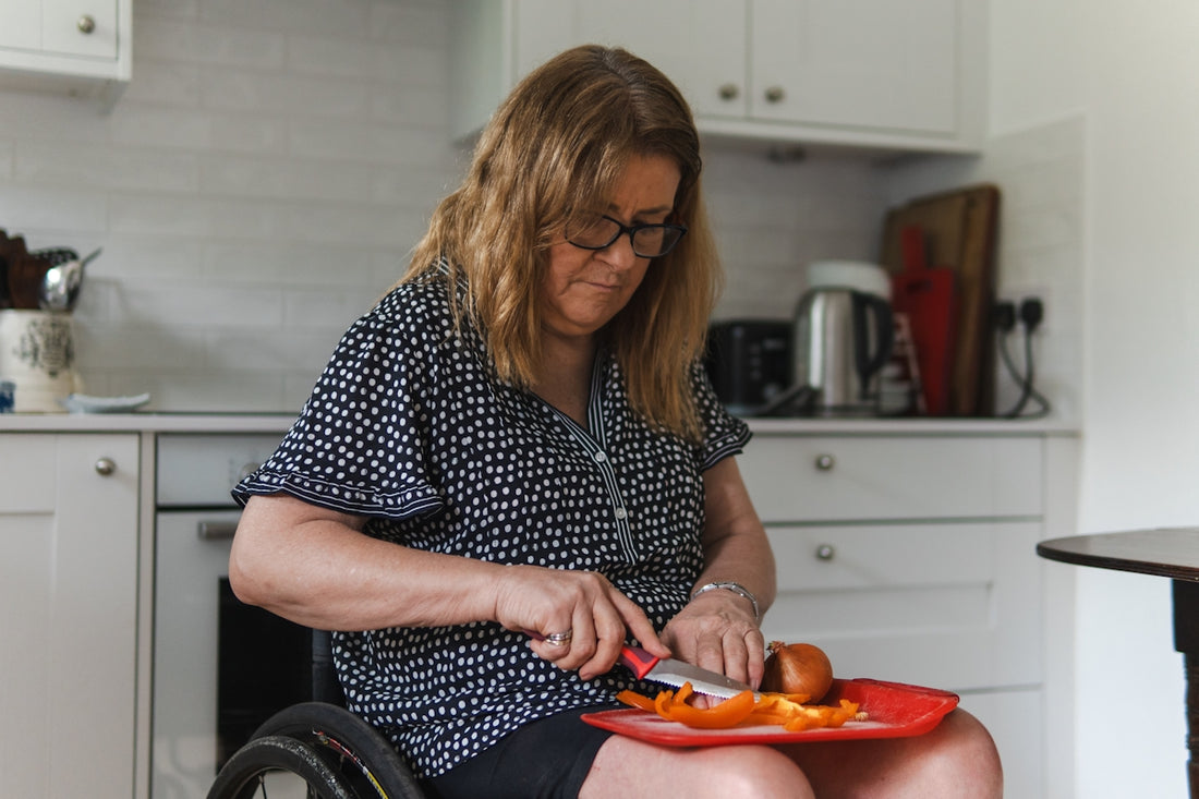 Woman in wheelchair preparing food in kitchen.