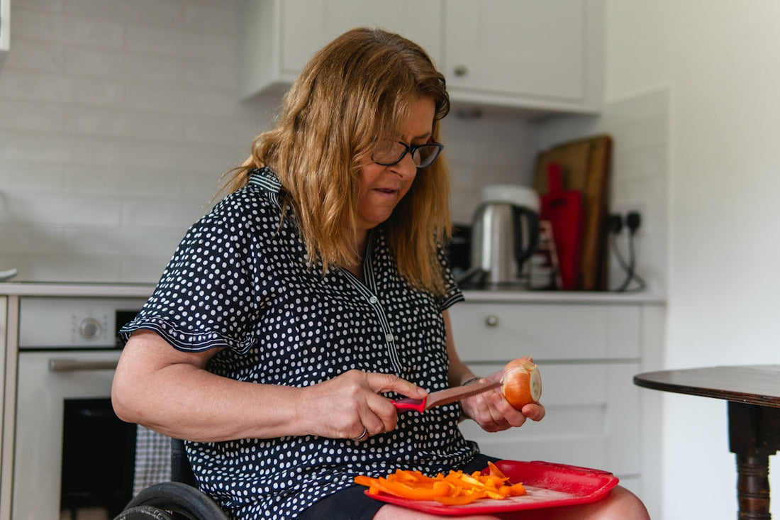 Woman in wheelchair peeling vegetables in kitchen