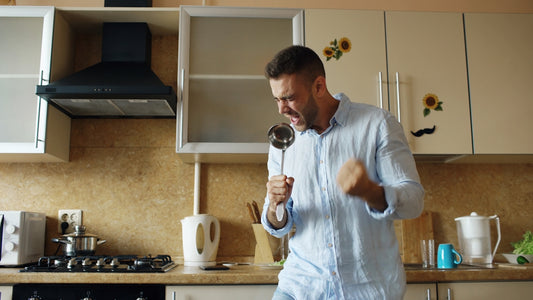 Man singing into ladle in kitchen
