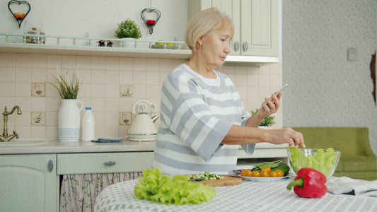 Elderly woman preparing salad in a kitchen