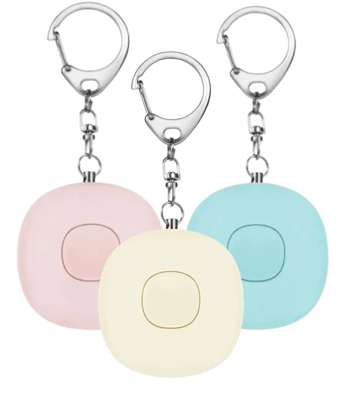 Three square keychain alarms in pastel pink, cream, and blue with central buttons and metal clip hooks