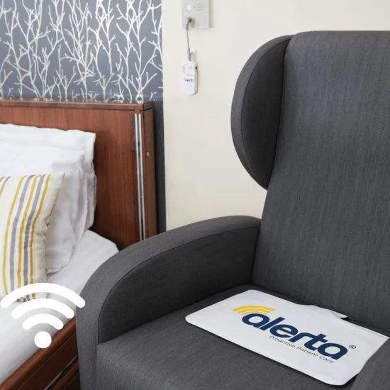 Alerta chair sensor alarm for elderly placed on a cozy armchair next to a bed