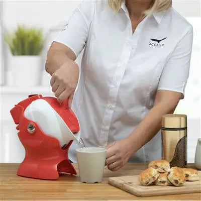 Uccello Kettle Tipper for disabled, pouring water from a stylish red kettle into a cup on a kitchen table